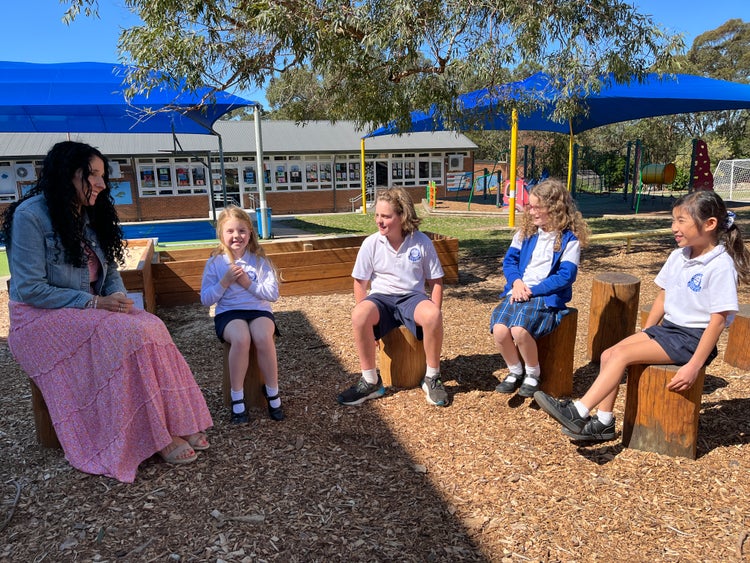 Staff member in playground with four smiling students